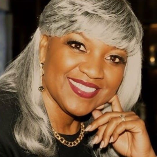 Woman with long silver hair smiling wearing a black shirt