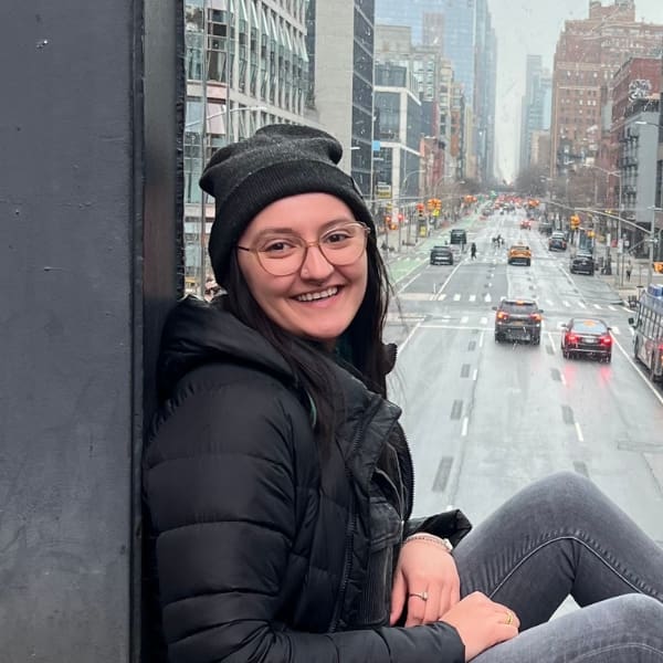 Girl smiling, sitting in front of window with a street behind her